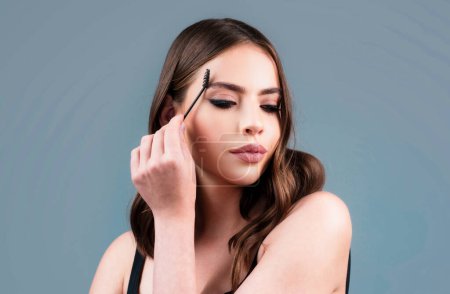 Photo for Combs eyebrows with a brush in a beauty salon. Sexy woman with long eyelashes and thick eyebrows. Microblading, modeling brows - Royalty Free Image