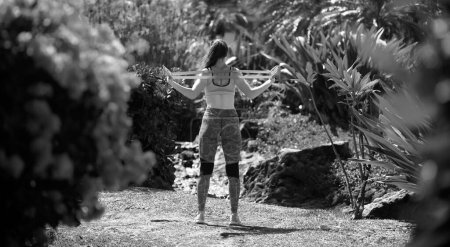 Téléchargez les photos : Vue arrière de l'entraînement femme en forme avec bande de résistance à l'extérieur - en image libre de droit