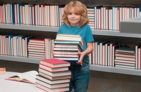 Photo for School boy with stack of books in library. School child student learning in class, study english language at school. Elementary school child. Portrait of funny pupil learning - Royalty Free Image