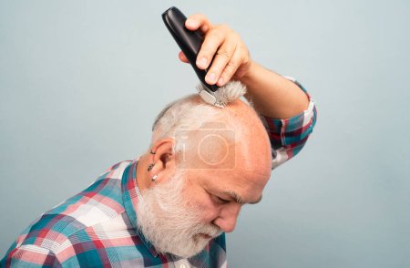 Foto de Senior con cortadora de cabello. Viejo hombre calvo cortador de pelo, calvicie madura y concepto de pérdida de cabello - Imagen libre de derechos