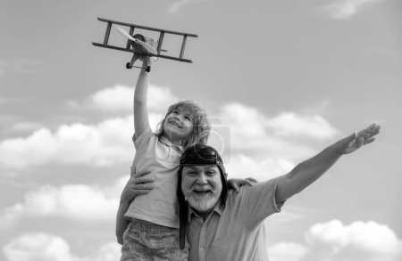 Téléchargez les photos : Enfant garçon et grand-père jouant avec un avion jouet sur fond de ciel d'été. Week-end avec grand-père - en image libre de droit