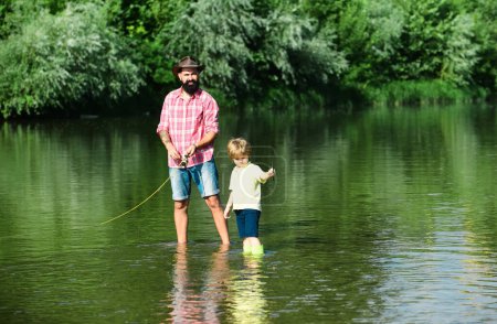 Téléchargez les photos : La fête des pères. Papa et son fils enfant pêchent sur fond de ciel. La pêche est devenue une activité récréative populaire - en image libre de droit