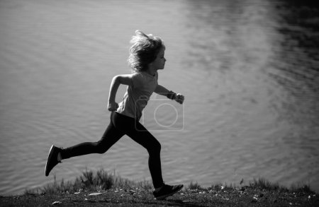 Foto de Corredores de niños corren en el parque. Niño corriendo en el parque en verano en la naturaleza. Deportes al aire libre y fitness, ejercicio y aprendizaje de competición para el desarrollo infantil. Correr por la mañana - Imagen libre de derechos