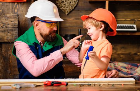 Foto de Construcción de herramientas. Padre enseñando a su hijo a usar herramientas de carpintería y martilleo. Padre ayudando a hijo en taller - Imagen libre de derechos