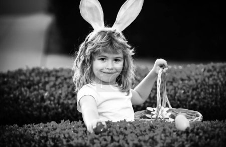 Photo for Child boy with easter eggs and bunny ears laying on grass. Child gathering eggs, easter egg hunt concept - Royalty Free Image