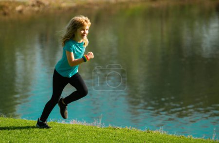 Téléchargez les photos : Enfant garçon jogging dans le parc en plein air. Enfant sportif courant dans la nature - en image libre de droit
