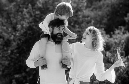 Photo for Dad mom and baby son playing together outdoors. Happy child showing his parents paper airplane. Happy loving family. Happy family on holiday - Royalty Free Image