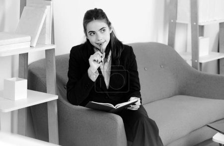 Portrait of young businesswoman accountant in formal wear at office work place. Successful female manager notes in notepad, beautiful secretary girl