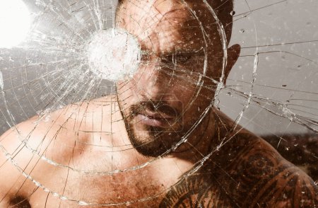 Photo for Anger. destruction. bullet hole in glass. broken glass because of hit. crush test. theft. emotional discharge. hispanic man broken mirror. macho man behind crushed glass. windscreen. windscreen crack. - Royalty Free Image
