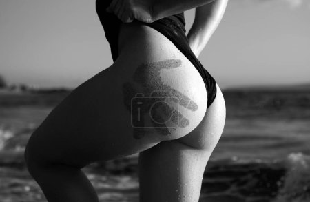 Téléchargez les photos : Beautiful woman with fingerprints of tne sand on her ass on Caribbean Sea in summer sunny day - en image libre de droit