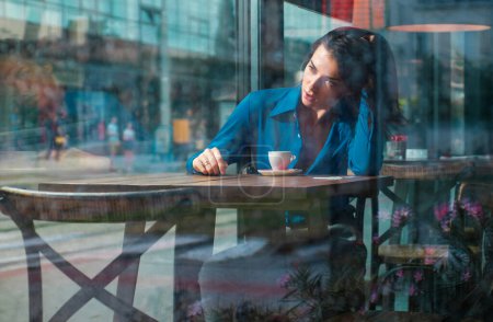 Téléchargez les photos : Concept réfléchi. Femme à un café tout en regardant à travers la vitre. Seule fille se sentir seule - en image libre de droit