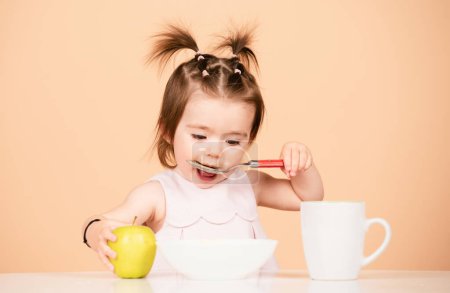 Foto de Lindo bebé come comida, bebés come. Niño comiendo comida saludable con una cuchara en el estudio, aislado. Cara divertida de los niños - Imagen libre de derechos