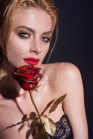 Téléchargez les photos : Portrait d'une jolie charmante fille rêveuse tenant des roses rouges, isolée sur fond de studio noir - en image libre de droit