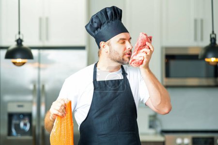 Photo for Chef in uniform cooking raw meat beef and fish salmon fillet in the kitchen. Restaurant menu concept. Male chef in working uniform, black apron, chef hat. Fish and meat or salmon and beef concept - Royalty Free Image