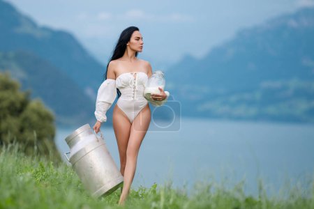 Photo for Sexy Milk. Young woman in lingerie drinking milk outside. Model drink Milk near green grass an Alpine lake. Young woman drinking milk from bottle on alpine mountain. Farm on Switzerland - Royalty Free Image
