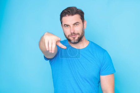 Photo for The point you. Happy handsome man pointing finger you away, isolated blue background. Excited man pointing a you great idea. Guy in blue t-shirt pointing you with his finger - Royalty Free Image