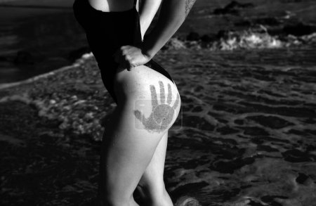 Foto de Closeup sexy butt with hand prints of woman in swimsuit at the barbados or virginia, beach. Women sensual body. Tanned booties of young model in bikini - Imagen libre de derechos