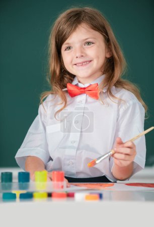 Photo for Portrait of little girl smiling happily while enjoying art and craft drawing lesson. Child girl drawing with coloring pens paintind - Royalty Free Image
