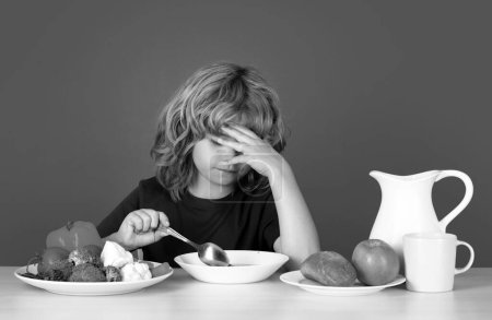 Photo for Bad appetite. Sad kid eating healthy food on studio iosolated background. Baby eat soup with spoon. Kid eating soup - Royalty Free Image