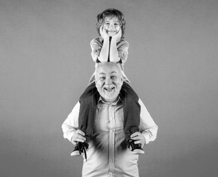 Photo for Old grandfather and young child grandson piggyback ride with funny face isolated on yellow. Elderly old relative with child - Royalty Free Image