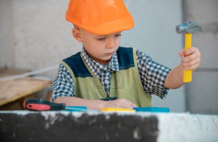 Foto de Child in building helmet, hard hat. Child dressed as a workman builder. Portrait little builder in hardhats. Little builder in helmet. Kids builder and repair - Imagen libre de derechos