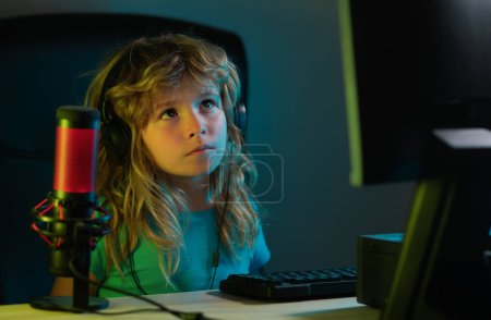 Foto de Niño jugando juegos de ordenador o estudiando en la computadora PC. Niño gamer en la noche neón iluminación - Imagen libre de derechos