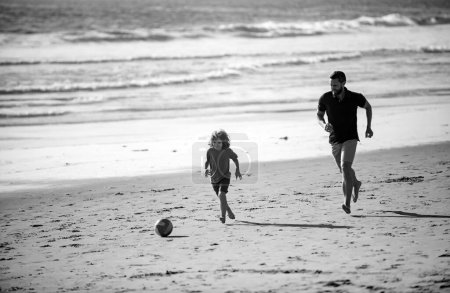 Foto de Padre e hijo juegan fútbol o fútbol en la playa. Papi con niño jugando en un día de verano - Imagen libre de derechos