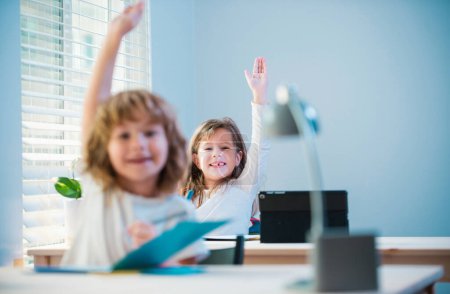 Photo for Cute little pupils raising hands during lesson. Children in classroom at school - Royalty Free Image