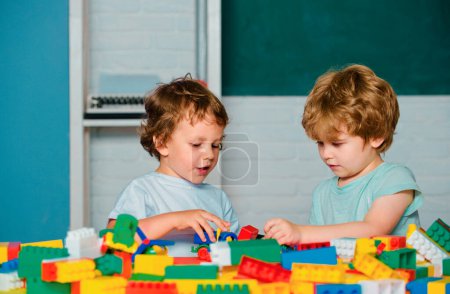 Foto de Alumnos de la escuela primaria. Los niños pequeños juegan con bloques, trenes y coches. Juguetes educativos para niños de preescolar y jardín de infantes - Imagen libre de derechos