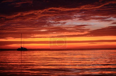 Photo for Sunset with large yellow sun under the sea surface. Calm ocean with sunset sky and sun through the clouds over. Calm ocean and sky background - Royalty Free Image