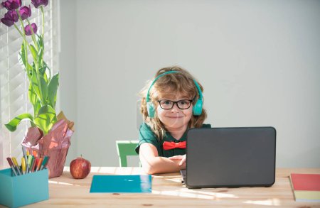 Téléchargez les photos : Child boy in headphones using a laptop at home. Homeschooling, online distant learning - en image libre de droit