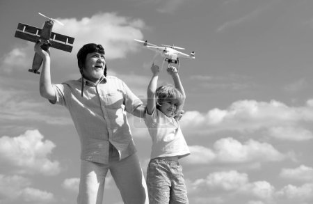 Photo for Old grandfather and young child grandson hold plane and drone quad copter against sky. Child pilot aviator with plane dreams of flying - Royalty Free Image