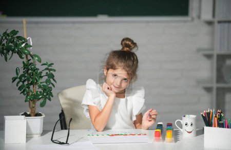 Téléchargez les photos : Les petites filles dessinent des images colorées avec des crayons de couleur dans la salle de classe de l'école. Peindre des enfants. Visage drôle d'enfants - en image libre de droit