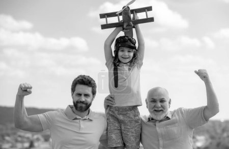Aktive Familienfreizeit mit Kindern. Sohn mit Vater und Großvater mit Spielzeugflugzeug spielen am Sommerhimmel