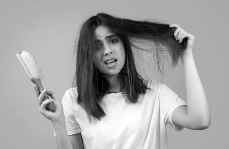 Foto de Mujer triste con el pelo cepillado. Problema de enredo. Chica infeliz con el pelo enredado. Peinado dañado del cabello - Imagen libre de derechos
