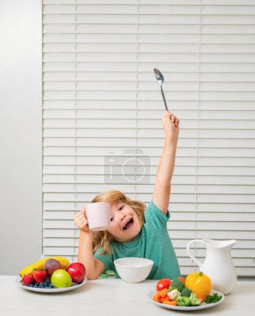 Foto de Gracioso niño sorprendido emocionado desayunando. Leche, verduras y frutas Alimentación saludable para niños - Imagen libre de derechos