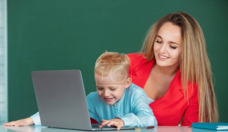 Photo for Mother and son together using computer laptop. Teacher explains lesson to school child. Elementary school kids learning - Royalty Free Image