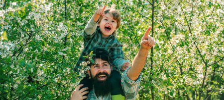 Photo for Banner for fathers day or father and son on spring background. Father and son on spring blossom garden background. Beautiful young smiling family having fun at farm yard - Royalty Free Image