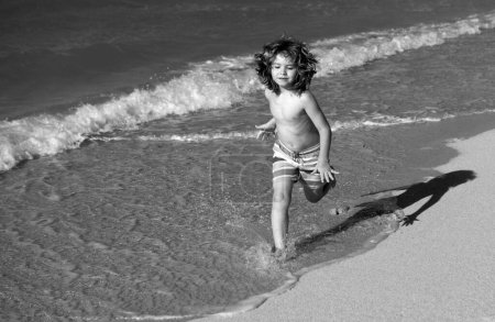 Foto de Un chico corriendo en la playa. Niño feliz correr en el mar en las vacaciones de verano. Viajes y aventuras en el mar o en el océano - Imagen libre de derechos