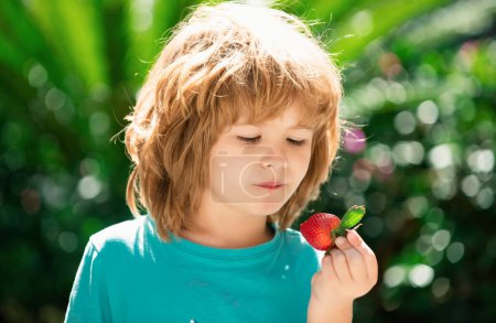 Foto de Niño feliz con fresas frescas. - Imagen libre de derechos