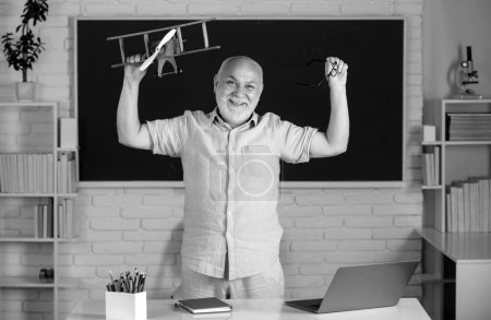 Photo for Funny senior teacher in the classroom on blackboard background. Old fun professor in high school or university. Teachers day - Royalty Free Image