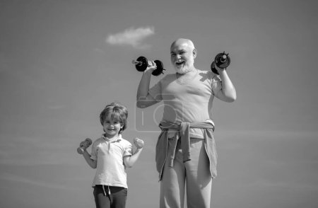 Téléchargez les photos : Drôle de vieil homme âgé et gamin avec des haltères. Soins de santé mode de vie joyeux. Famille active profiter du sport et de remise en forme - en image libre de droit