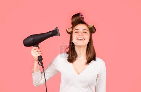 Foto de Woman with hair dryer after showering. Beautiful girl with straight hair drying hair with professional hairdryer - Imagen libre de derechos