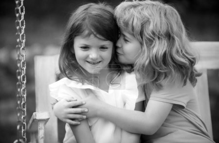 Photo for Two little children hug and kiss each other in summer garden. Kids couple in love. Friendship and childhood. Happy children having fun outdoors. Kids playing in spring park. Shy girl - Royalty Free Image