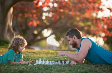 Téléchargez les photos : Père et fils enfant jouant aux échecs passer du temps ensemble en plein air - en image libre de droit
