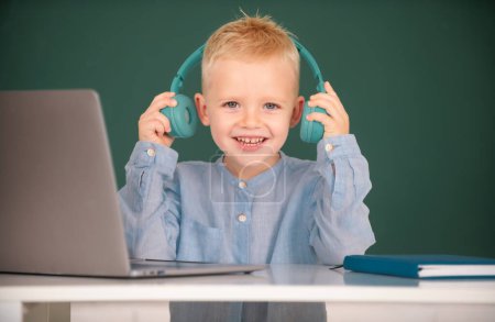Téléchargez les photos : Enfant garçon dans les écouteurs étude en ligne, enfant dans les écouteurs prendre Internet leçon web. - en image libre de droit
