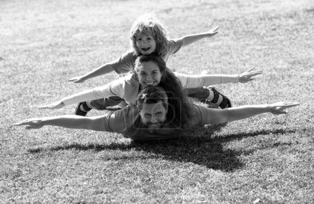 Foto de Familia joven con niños divirtiéndose en la naturaleza. Concepto de mosca, niño pequeño está sentado pickaback mientras imita el vuelo - Imagen libre de derechos