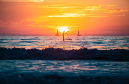 Téléchargez les photos : Homme pagaie lors d'un beau lever de soleil. Coucher de soleil sur la mer. Lever de soleil à la plage. Coloré océan plage lever de soleil - en image libre de droit