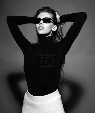 Téléchargez les photos : Femme sexy en lunettes de soleil noires. Portrait de fille sensuelle regardant loin isolé sur gris - en image libre de droit