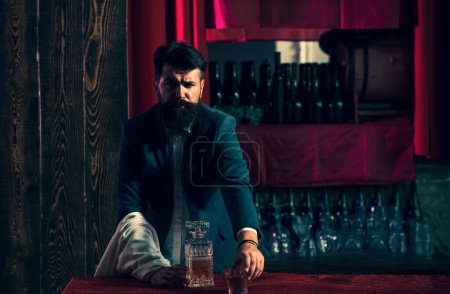 Téléchargez les photos : Beau barman barbu appuyé sur le comptoir du bar. Expert bar man prépare un cocktail au night club - en image libre de droit